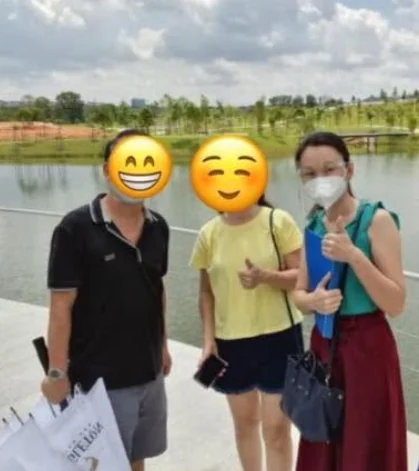 Katherine Leow standing with two people, with their faces covered for privacy
